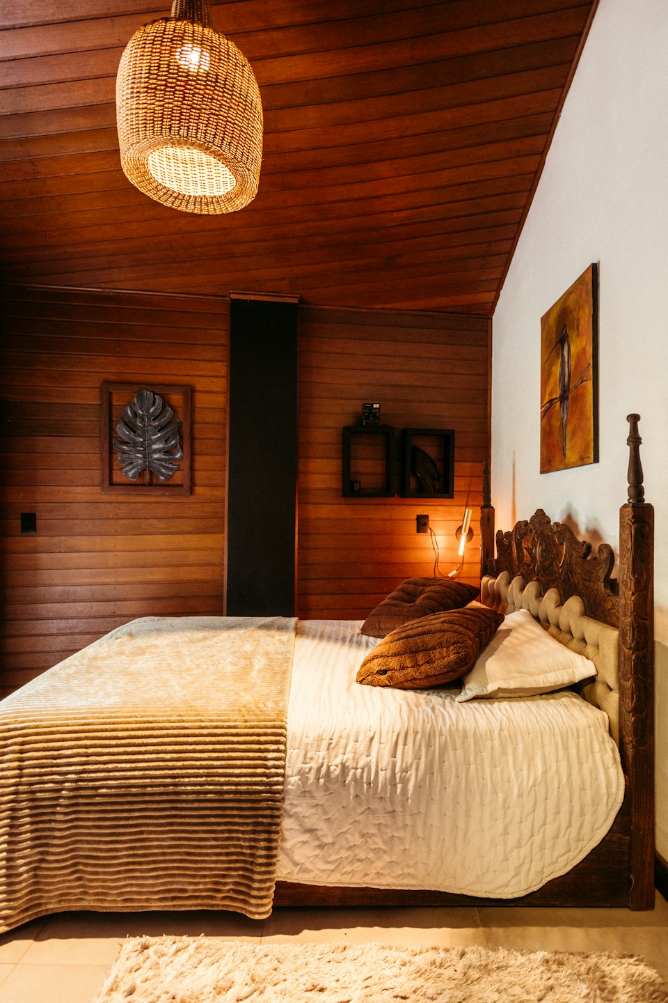Una cama con ropa de cama neutra en un dormitorio de madera.